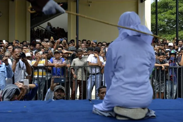An 18-year-old Indonesian woman is caned in public in Banda Aceh on January 31, 2019, as punishment for being caught cuddling with her boyfriend. Two teenagers were whipped in Indonesia's Aceh province on January 31 after they were caught cuddling in public – a crime under the conservative region's Islamic law. (Photo by Chaideer Mahyuddin/AFP Photo)
