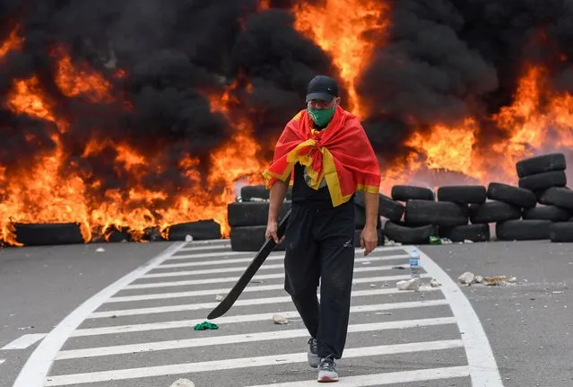 A man walks past burning tires at a barricade set up to block access roads to the historic city of Cetinje during a protest against the inauguration of the new head of the Serbian Orthodox Church on September 5, 2021 in Montenegro. The new head of the Serbian Orthodox Church in Montenegro was inaugurated, arriving by helicopter under the protection of police who dispersed protesters with tear gas. The decision to anoint Bishop Joanikije as the new Metropolitan of Montenegro at the historic monastery of Cetinje has aggravated ethnic tension in the tiny Balkan state. (Photo by Savo Prelevic/AFP Photo)