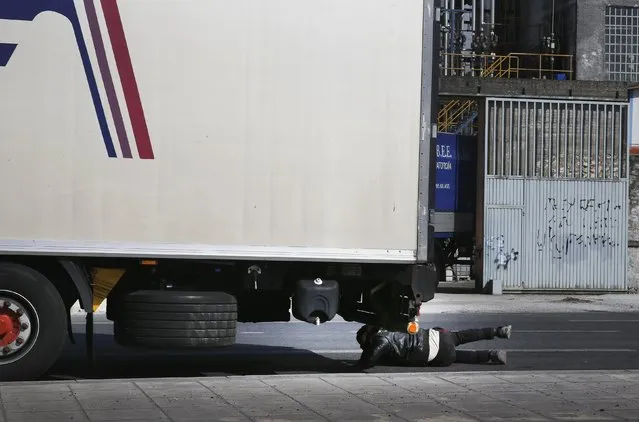 An African immigrant tries to sneak under a truck, which briefly stopped at a traffic light, while trying to enter the ferry terminal in the western Greek town of Patras April 28, 2015. (Photo by Yannis Behrakis/Reuters)