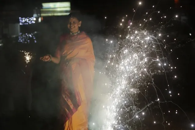 A woman celebrates Diwali at Shivaji park in Mumbai, India, Thursday, November 4, 2021. Diwali, the festival of lights, is one of Hinduism's most important festivals dedicated to the worship of Lakshmi, the Hindu goddess of wealth. (Photo by Rajanish Kakade/AP Photo)