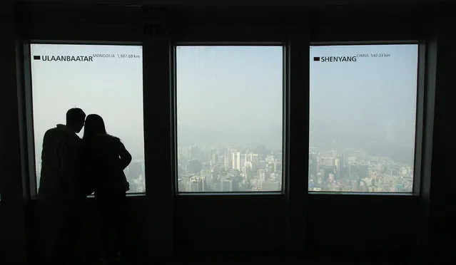 A couple watches the Seoul skyline covered with a thick haze at Seoul Tower's observation deck in Seoul, South Korea, Wednesday, February 26, 2014. The Seoul metropolitan government issued a dust warning, urging people to stay indoors. (Photo by Ahn Young-joon/AP Photo)
