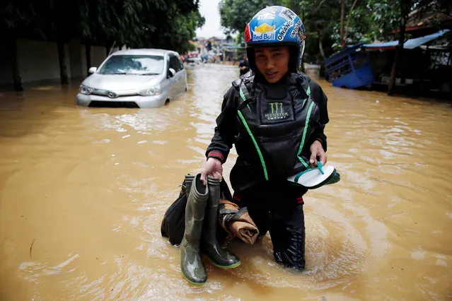 A man carries his belonging as he wades through floodwaters in a flood-hit area in Jatinegara district, Jakarta, Indonesia, February 16, 2017. (Photo by Reuters/Beawiharta)