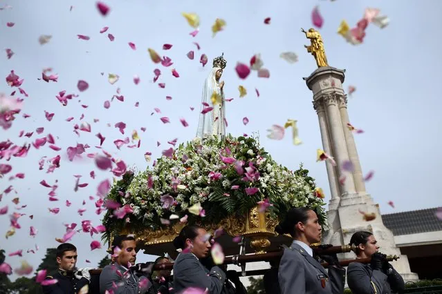 Worshipper throw flower petals at the statue of the Our Lady of Fatima as it is carried at the Our Lady of Fatima shrine, in Fatima, central Portugal, Wednesday, May 13, 2015. (Photo by Francisco Seco/AP Photo)