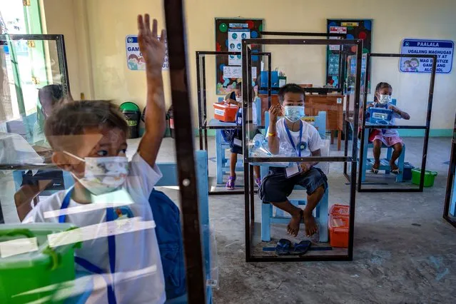 Elementary students sit inside dividers as preventive measure against COVID-19, as they attend the first day of physical classes at Longos Elementary School on November 15, 2021 in Alaminos, Pangasinan province, Philippines. After almost two years since schools closed due to the COVID-19 pandemic, the Philippines resumed limited face-to-face classes in 100 schools across the country on November 15. The Philippines is the last country in the world to reopen schools since the pandemic began, after Venezuela reopened schools on October 25. Critics are blaming the government's lackluster pandemic response for the prolonged closure of schools. (Photo by Ezra Acayan/Getty Images)