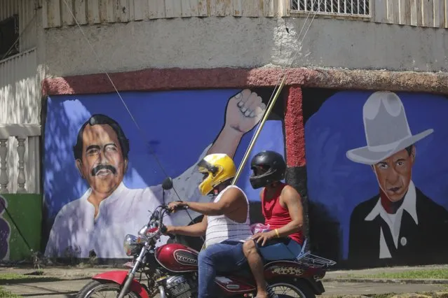 A motorcyclist rides past a mural of Nicaraguan President Daniel Ortega, left, and revolutionary hero Cesar Augusto Sandino during general elections in Managua, Nicaragua, Sunday, November 7, 2021. Ortega seeks a fourth consecutive term against a field of little-known candidates while those who could have given him a real challenge sit in jail. (Photo by Andres Nunes/AP Photo)
