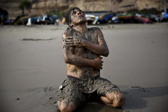 In this May 14, 2015 photo, Berto Nestaris covers his body with sand on Fishermen's Beach in Lima, Peru. Berto, a 55-year-old sociologist, said therapeutic massages using sea sand helps his circulation and nervous system. (Photo by Rodrigo Abd/AP Photo)