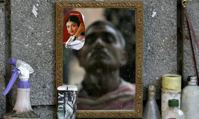 A man is seen reflected in a mirror as he gets a shave at a roadside barber shop in New Delhi in this June 29, 2007 file photo. (Photo by Adnan Abidi/Reuters)