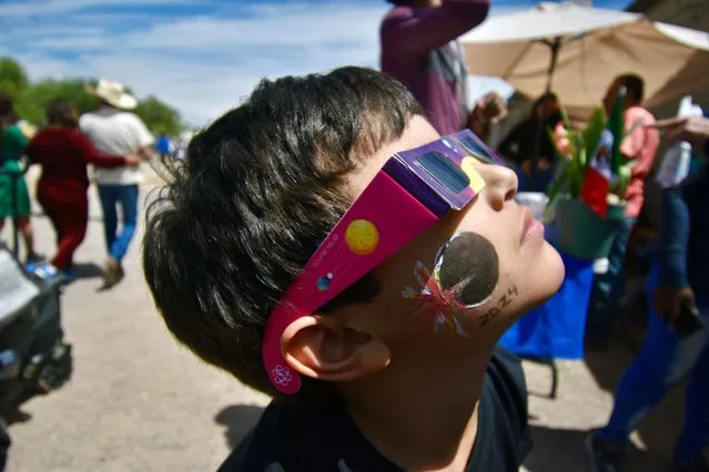A kid wears special sunglasses to observe the total solar eclipse in Nazas, Durango state, Mexico on April 8, 2024. This year's path of totality is 115 miles (185 kilometers) wide and home to nearly 32 million Americans, with an additional 150 million living less than 200 miles from the strip. The next total solar eclipse that can be seen from a large part of North America won't come around until 2044. (Photo by Haaron Alvarez/AFP Photo)