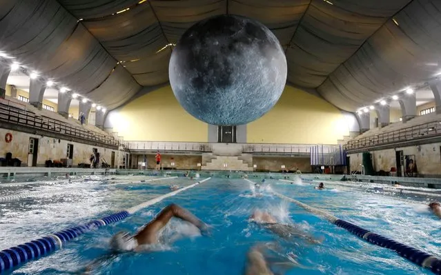 Swimmers practice as the installation “Museum of the Moon”, a seven meters diameter reproduction of the moon by British artist Luke Jerramche, is suspended above the Cozzi swimming pool in Milan, Italy, Saturday, June 15, 2019. (Photo by Luca Bruno/AP Photo)