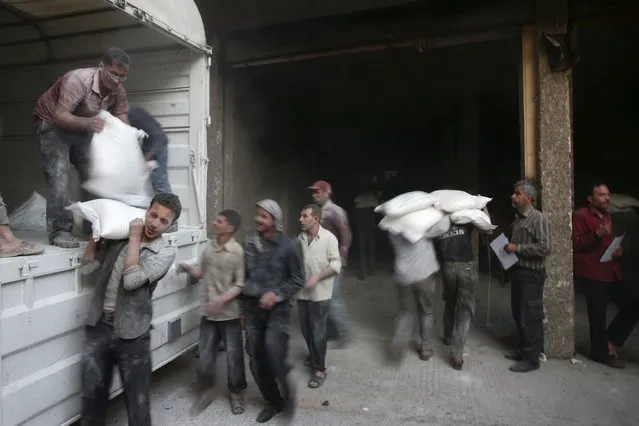 Men unload flour from a Red Crescent and United Nations aid convoy in the rebel held besieged town of Hamoria area, in the eastern suburbs of Damascus, Syria April 19, 2016. (Photo by Bassam Khabieh/Reuters)