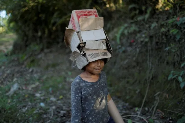 A boy plays with cardboard boxes the day before the interment of recently exhumed human remains dating back to Guatemala's 36-year civil war, in Sepur Zarco, Guatemala on December 9, 2021. (Photo by Sandra Sebastian/Reuters)