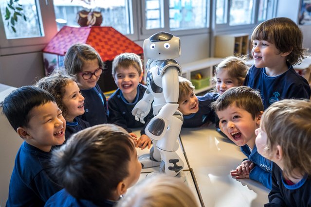 Preschoolers interact with educational and interactive robot Nao at “La Nanosphere” creche in the university campus of the Swiss Federal Institute of Technology in Lausanne, western Switzerland, on February 23, 2024. Nao has been a regular visitor at the Nanosphere nursery since the New Year. In a circle on the nursery floor, youngsters listen excitedly to Nao's words of wisdom as the friendly robot from another planet answers their questions about giraffes and broccoli. (Photo by Fabrice Coffrini/AFP Photo)