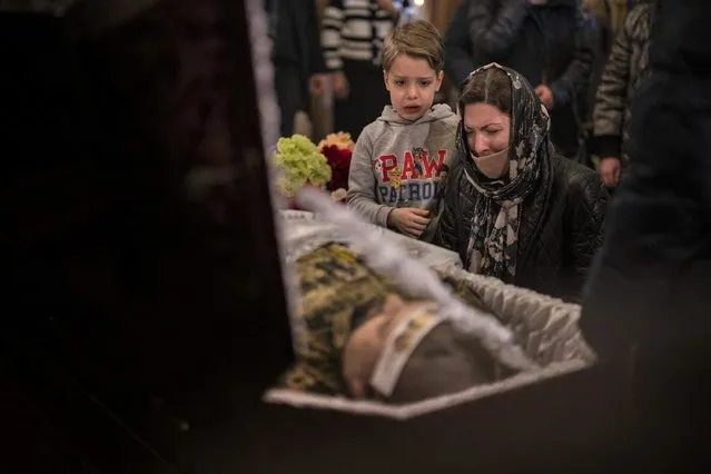 A woman and a boy react next to the body of Ukrainian Army captain Anton Sydorov, 35, killed in eastern Ukraine, during his funeral, in Kyiv, Ukraine, Tuesday, February 22, 2022. Western leaders said Tuesday that Russian troops have moved into rebel-held areas in eastern Ukraine after President Vladimir Putin's recognized their independence – but some indicated it was not yet the long-feared full-fledged invasion as confusion reigned in the region. (Photo by Emilio Morenatti/AP Photo)