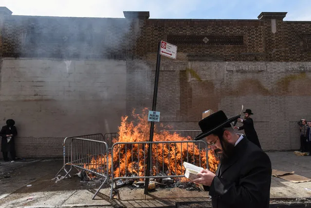 People participate in a Jewish religious ceremony called Srifes Chumetz involving a ritual burning of a bonfire before the start of Passover in the Brooklyn borough in New York, NY, April 10, 2017. (Photo by Stephanie Keith/Reuters)