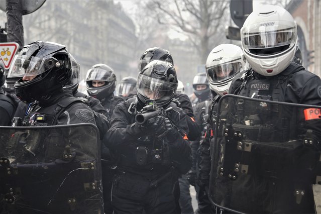 A polie officer aims his teargas gun during a demonstration in Paris, Saturday, March 11, 2023. Opponents of President Emmanuel Macron's hotly contested plan to raise the retirement age from 62 to 64 were taking to the streets of France on Saturday for the second time this week in what union's hope will be a new show of force meant to push the government to back down. (Photo by Lewis Joly/AP Photo)