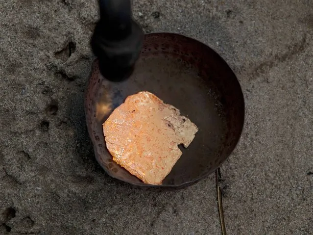 A miner melts an amalgam of gold and mercury to burn off the mercury in La Pampa in Peru's Madre de Dios region. This rudimentary process of extracting the gold from the amalgam, releases mercury vapors, adding to the contamination that is resulting in the deforestation of thousands of acres of the Amazon rainforest. (Photo by Rodrigo Abd/AP Photo)