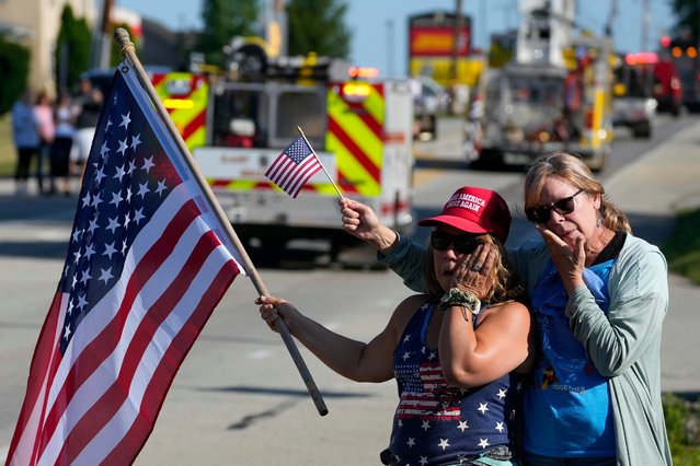 Merri Cambo, left, of Saxonburg, Pa., and her friend, Jane Wesolosky, of Buffalo, Pa., react as the funeral procession for Corey Comperatore passes by, Friday, July 19, 2024, in Sarver, Pa. Comperatore, a former fire chief, was shot and killed while attending a weekend rally for former President Donald Trump. (Photo by Matt Slocum/AP Photo)