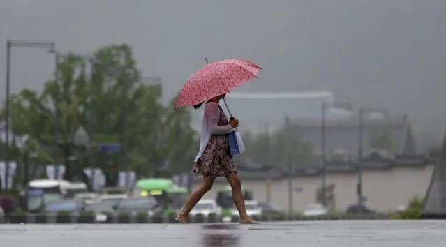 A woman holds an umbrella in the rain as she walks through downtown Seoul, South Korea, Monday, July 13, 2015. (Photo by Lee Jin-man/AP Photo)