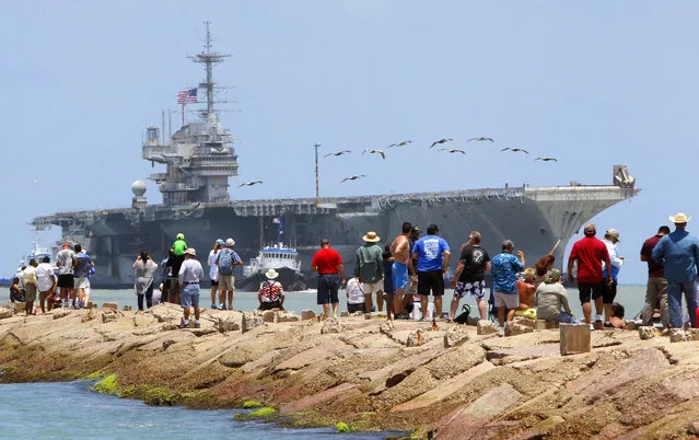 People line the jetties as they watch the USS Independence towed into the Brownsville Ship Channel for salvage on Thursday, June 1, 2017, on South Padre Island, Texas. A group of the ship’s past crew members stood and watched as the ship was towed up the channel toward International Shipbreaking Ltd., the recycling company that won the contract to scrap the ship. (Photo by Nathan Lambrecht/The Monitor via AP Photo)