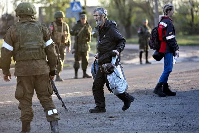 A man, who left a shelter in the Metallurgical Combine Azovstal walks to a bus between servicemen of Russian Army and Donetsk People’s Republic militia in Mariupol, in territory under the government of the Donetsk People’s Republic, eastern Ukraine, Friday, May 6, 2022. (Photo by Alexei Alexandrov/AP Photo)
