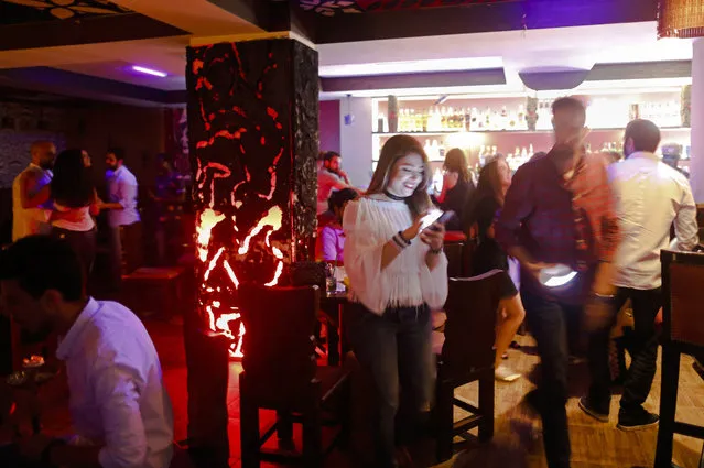 In this May 18, 2017. photo, a Syrian checks her mobile as others dance at a popular bar in the Old City in Damascus, Syria,  Across the capital, new shops are sprouting up, business is brisk, and some people who fled the war years ago are contemplating a return. The Syrian civil war is likely to drag on for years, but in the seat of President Bashar Assad’s government, there is a general feeling that the six-year conflict is winding down. (Photo by Hassan Ammar/AP Photo)