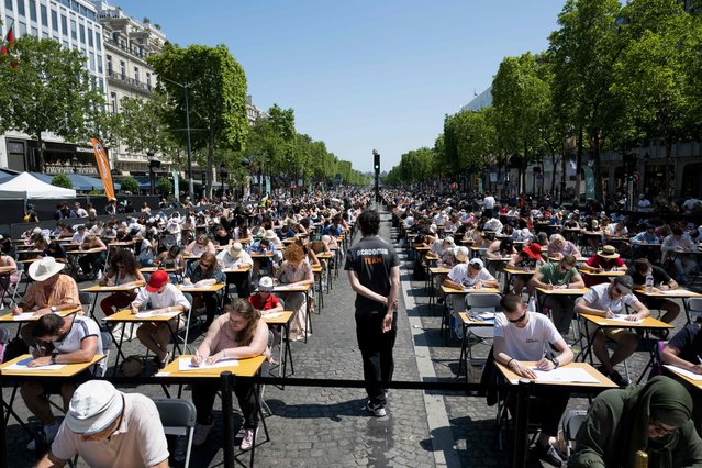 Participants attempt to beat the record of the “World's Biggest Dictation” on the prestigious Champs-Elysees Avenue, transformed into a giant classroom, in Paris on June 4, 2023. (Photo by Alain Jocard/AFP Photo)