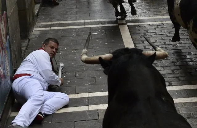 A runner falls in front of a Torrestrella fighting bull at the Estafeta corner during the first running of the bulls at the San Fermin festival in Pamplona July 7, 2014. One runner was gored and four others suffered light injuries in a run that lasted two minutes and twenty five seconds, according to local media. (Photo by Vincent West/Reuters)