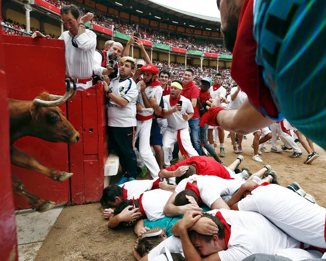 A bull from the Nunez del Cuvillo bull ranch enters the bullring as a group of “mozos” or runners protect themselves laining on the ground at the end of the seventh “encierro” or bull run of the Sanfermines 2017, in Pamplona, Spain, 13 July 2017. The festival, locally known as Sanfermines, is held annually from 06 to 14 July in commemoration of the city's patron saint San Fermin. (Photo by Jesus Diges/EPA)