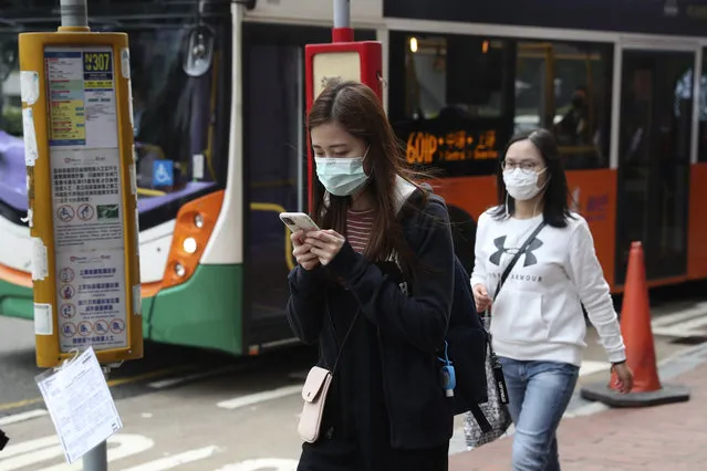 People wear protective face masks on a street in Hong Kong, Friday, January 24, 2020. China closed off a city of more than 11 million people Thursday, halting transportation and warning against public gatherings, to try to stop the spread of a deadly new virus that has sickened hundreds and spread to other cities and countries in the Lunar New Year travel rush. (Photo by Achmad Ibrahim/AP Photo)