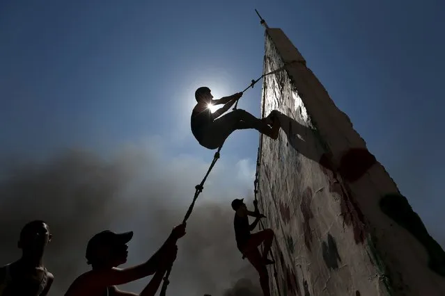 Young Palestinians climb a wall with a rope during a military-style exercise at a summer camp organized by Islamic Jihad movement, in Khan Younis in the southern Gaza Strip, August 13, 2015. (Photo by Ibraheem Abu Mustafa/Reuters)