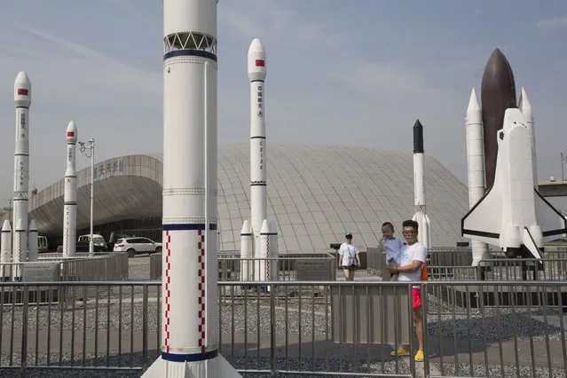 A man holds a child as they visit a park with replicas of foreign and domestic space vehicles displayed in Beijing, China, Sunday, June 26, 2016. China on Sunday recovered an experimental probe launched aboard a new generation rocket, marking another milestone in its increasingly ambitious space program that envisions a mission to Mars by the end of the decade. (Photo by Ng Han Guan/AP Photo)