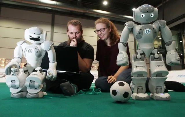 Jonathan Brast and Sina Ditzel work with a laptop on the functions of a robot that can play soccer in a hall on the fairgrounds in Leipzig, Germany, June 29, 2016. (Photo by Sebastian Willnow/EPA)