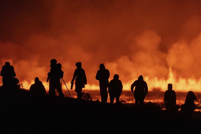 Tourists and visitors try to get a view of a volcanic eruption from a distance at the intersection between Reykjanesbraut, Iceland, and the road to Grindavik, Thursday, August 22, 2024. (Photo by Marco di Marco/AP Photo)