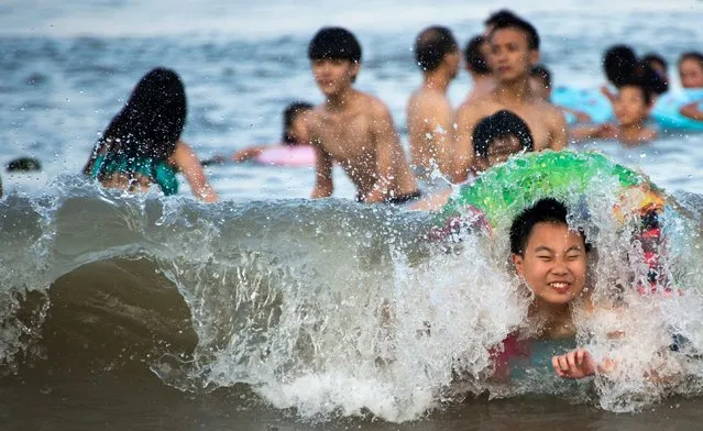Children play with swimming rings at the beach in Xiangshan on the East China Sea on August 3, 2014.  As temperatures rose to over 35 degrees Centigrade (95F) many people came out to cool off in the water. (Photo by Johannes Eisele/AFP Photo)