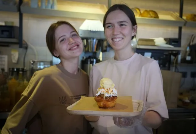 Waitresses smile as they hold a puff pastry cake topped with meringue and ice cream, named after British Prime Minister Boris Johnson at Zavertailo’s Café in Kyiv, Ukraine, Wednesday, June 8, 2022. Johnson may have been shown the door in Britain, but he remains a popular figure in Ukraine, where he is widely admired for his uncompromising support for the country’s effort to defeat the Russian invasion. (Photo by Efrem Lukatsky/AP Photo)