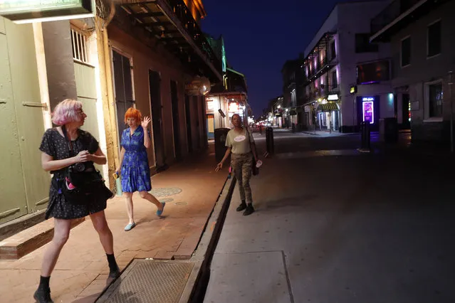 Jessica Fender, center, and Kerry Maloney, left, shy away from a woman asking for money after they felt she got too close, as the two exercise social distancing due to the new coronavirus outbreak, on a deserted Bourbon Street, normally busy with tourists and revelers, in New Orleans, Monday, March 23, 2020. Louisiana Gov. John Bel Edwards issued a shelter-in-place order for Louisiana which took effect today. (Photo by Gerald Herbert/AP Photo)