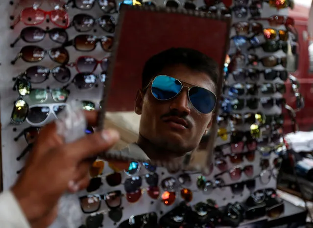 A customer tries on a pair of sunglasses at a stall selling glasses ahead of Eid al-Fitr in Karachi, Pakistan July 4, 2016. (Photo by Akhtar Soomro/Reuters)