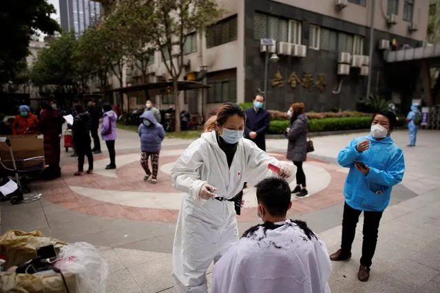 Barber Xiong Juan, 39, cuts a customer's hair at a residential compound in Wuhan, March 30, 2020. Xiong, 39, now spends her days riding around on her electric bicycle and offering her services to local residents who like her were stuck at home after authorities ordered the lockdown. (Photo by Aly Song/Reuters)