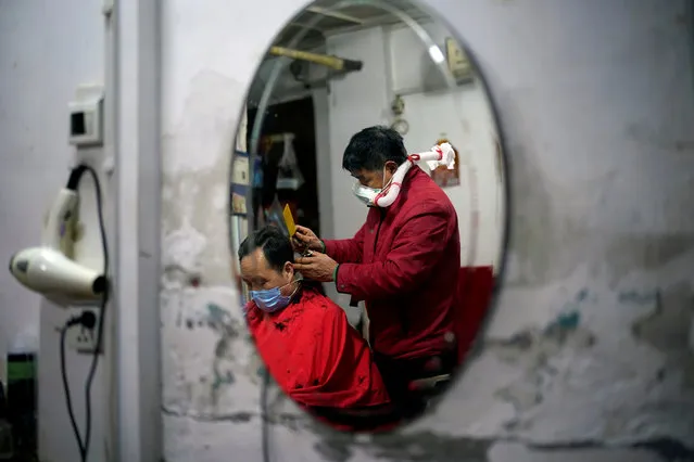 Yang Guangyu, 54, a local barber working in his shop at a blocked residential area, wears his handmade mask assembled from a water bottle, mask and a plastic pipe, as he works after the lockdown was lifted in Wuhan, capital of Hubei province and China's epicentre of the novel coronavirus disease (COVID-19) outbreak on April 11, 2020. (Photo by Aly Song/Reuters)