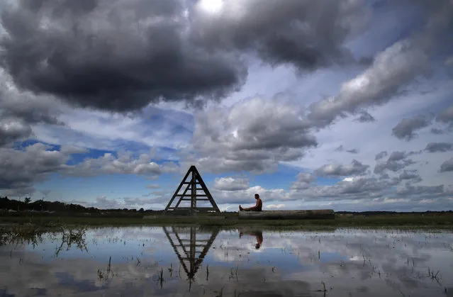 Brian Ellis meditates under clearing skies on a log near an exercise structure at Back Cove, Thursday, September 7, 2016, in Portland, Maine. A rain storm that left behind large puddles has moved on, allowing for drier weather for the remainder of the week. (Photo by Robert F. Bukaty/AP Photo)