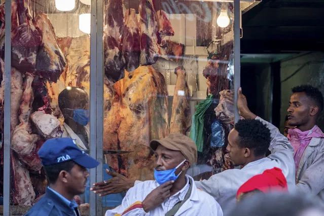 Butchers and others wear masks to curb the spread of the new coronavirus, as they sell lamb, beef, and goat meat for Orthodox Easter, at a butchers shop in Addis Ababa, Ethiopia Sunday, April 19, 2020. (Photo by Mulugeta Ayene/AP Photo)