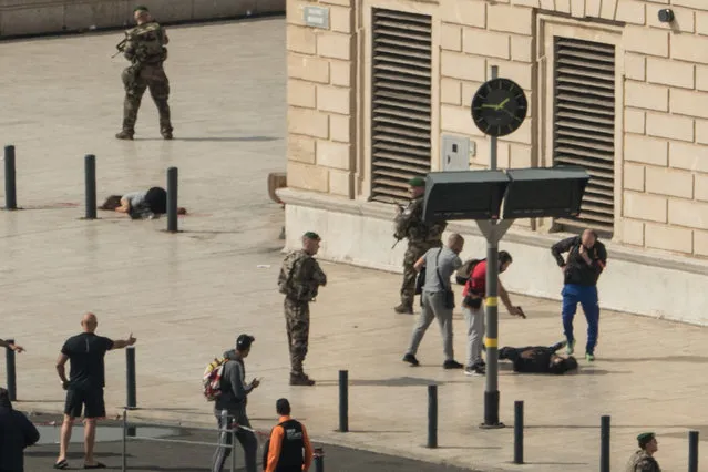 French police point a gun at a man on the ground (C) as a stabbed woman lies (L) while soldiers secure the area following an attack on October 1, 2017 at the Saint-Charles main train station in the French Mediterranean city of Marseille. A suspected Islamist knifeman killed two women at the main train station in Marseille on October 1 before being shot dead by soldiers on patrol, local officials and police said. (Photo by Paul-Louis Leger/AFP Photo)