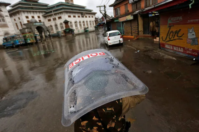 An Indian policeman uses his shield to cover himself from rain as he patrols a deserted road during a curfew in downtown Srinagar July 27, 2016. (Photo by Danish Ismail/Reuters)