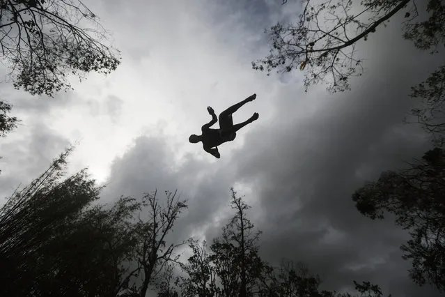 A man dives into the Espiritu Santo river from a rope swing before heavy afternoon rains more than two weeks after Hurricane Maria hit the island, on October 8, 2017 in Palmer, Puerto Rico. Only 11.7 percent of Puerto Rico's electricity has been restored and some residents are going to the river to cool off and relax while others go to bathe, wash clothes, or gather water. The area borders the El Yunque National Forest, the United States' only tropical rainforest, which was heavily damaged by the hurricane. Puerto Rico experienced widespread damage including most of the electrical, gas and water grid as well as agriculture after Hurricane Maria, a category 4 hurricane, swept through. (Photo by Mario Tama/Getty Images)