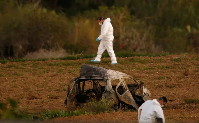 Forensic experts walk in a field after a powerful bomb blew up a car (Foreground) and killed investigative journalist Daphne Caruana Galizia in Bidnija, Malta, October 16, 2017. (Photo by Darrin Zammit Lupi/Reuters)