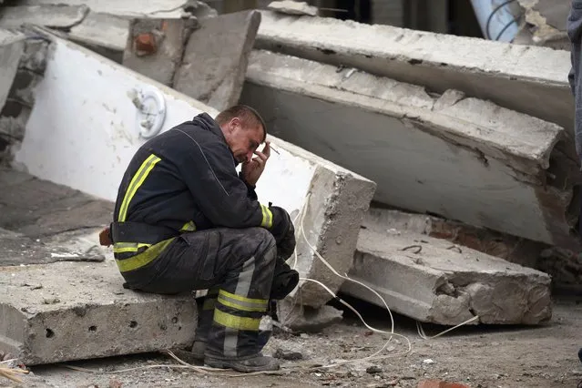 A rescue worker takes a pause as he sits on the debris at the scene where a woman was found dead after a Russian attack that heavily damaged a school in Mykolaivka, Ukraine, Wednesday, September 28, 2022. (Photo by Leo Correa/AP Photo)