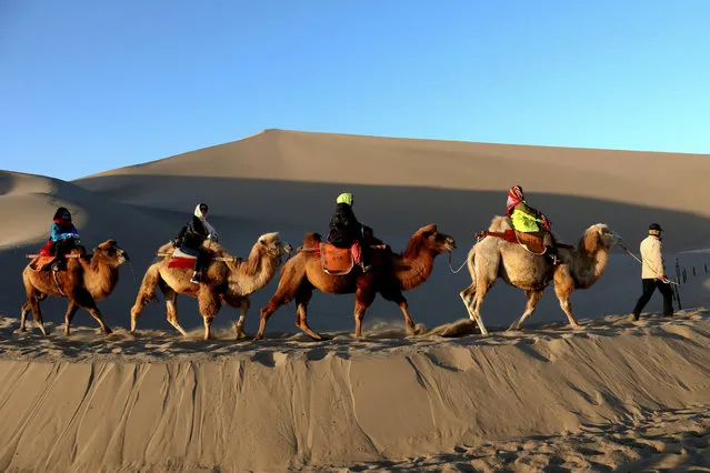 Tourists ride camels in the Mingsha Sand Dunes near Crescent Moon Spring on the outskirts of Dunhuang, Gansu province, China October 28, 2017. (Photo by Reuters/China Stringer Network)