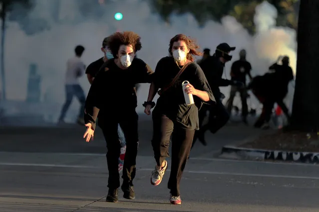 Protesters run away as police shoot tear gas and flash grenades to disperse the crowd on Broadway near the Oakland Police Department during the fourth day of protests over George Floyd's death by the Minneapolis police in Oakland, Calif., on Monday, June 1, 2020. (Photo by Ray Chavez/Bay Area News Group)