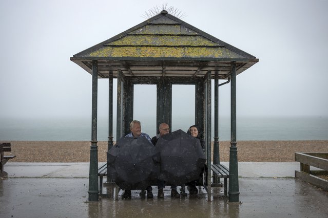 People seek shelter at the seafront during heavy rain on August 17, 2022 in Seaford, United Kingdom. After the UK experienced a second summer heatwave, storms are expected starting in the north of the country from Monday moving to the whole country by Wednesday, with flood alerts issued by the Met Office. (Photo by Dan Kitwood/Getty Images)