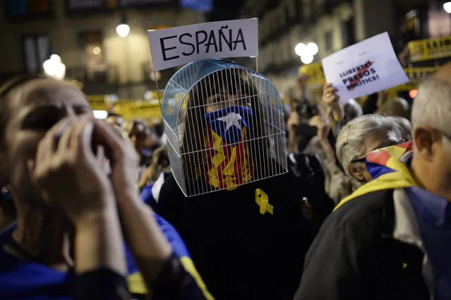 A woman with a cage over her head and her face covered with a Catalan pro-independence Estelada flag takes part in a demonstration in Barcelona on November 3, 2017 to protest against the detention of Catalan officials in Madrid. A judge in Madrid was set to issue an EU arrest warrant for Catalonia's deposed leader over his region's tumultuous independence drive, in a move likely to take tensions to a new level in Spain's worst political crisis in decades, a day after other leading figures in Catalonia's secession push were sent to jail pending possible trial. (Photo by Josep Lago/AFP Photo)